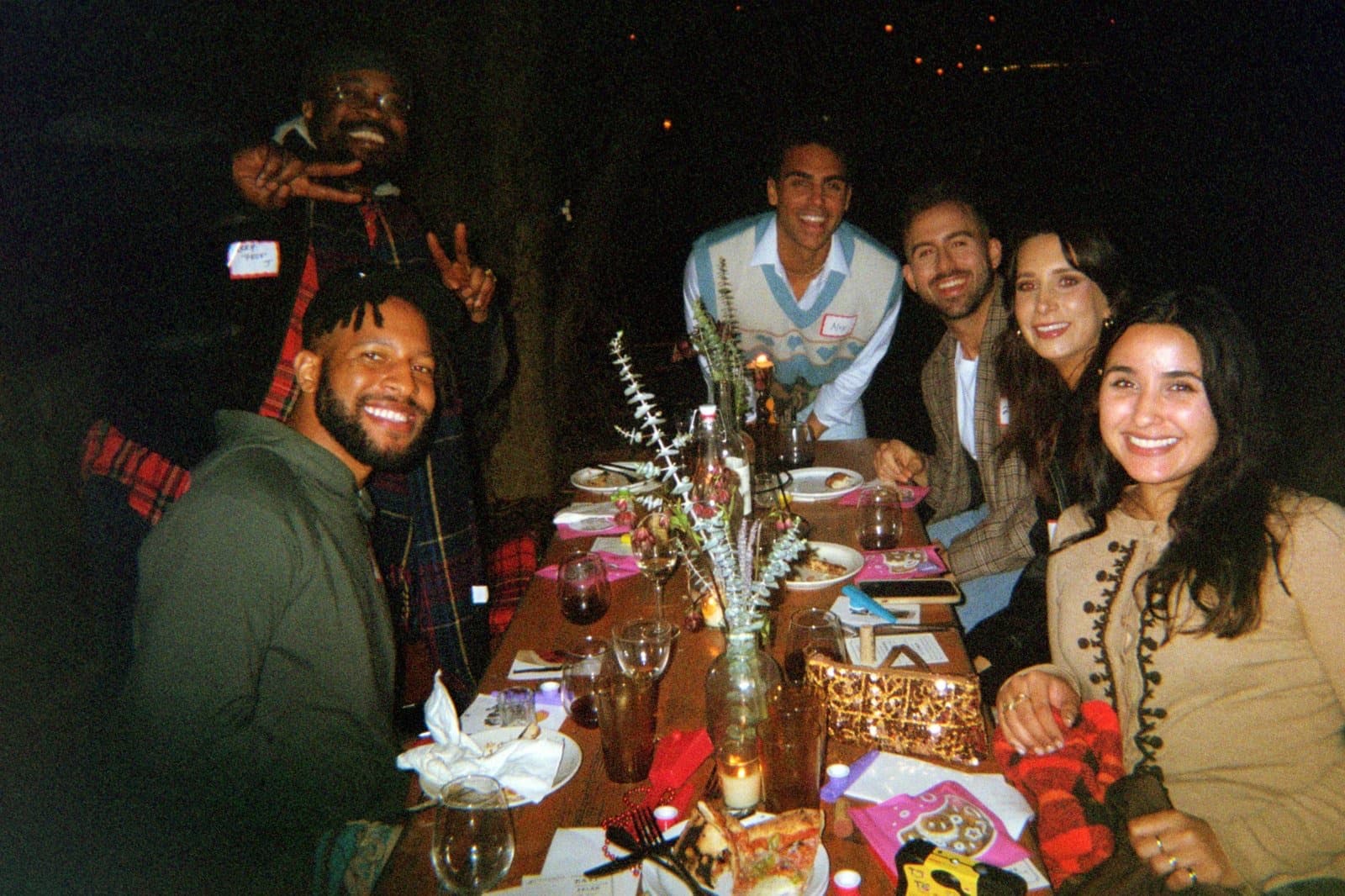 A smiling group posing along a long dinner table