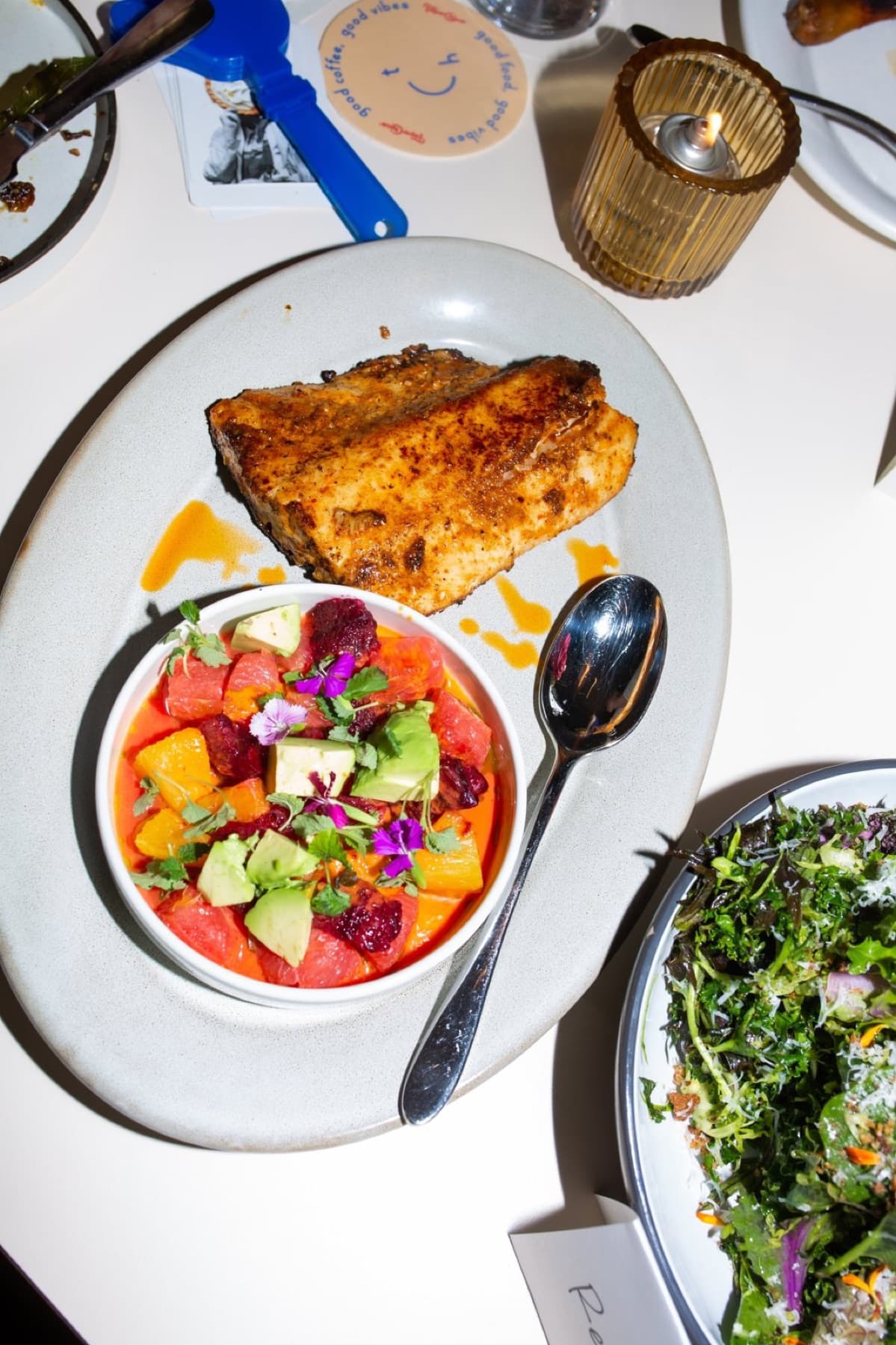 A plate of fish beside a bowl of fruit salad